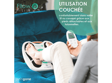 Charger l&#39;image dans la galerie, Une femme se reposant avec ses pieds sur un appareil blanc, tenant une télécommande, sur un canapé sarcelle.
