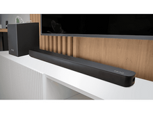 Charger l&#39;image dans la galerie, Barre de son et caisson de basses noirs sur étagère blanche, mur en bois.
