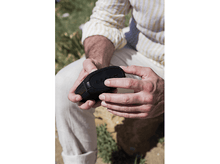 Charger l&#39;image dans la galerie, Homme tenant un haut-parleur noir. Le haut-parleur est noir. Arrière-plan ensoleillé flou.
