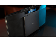 Charger l&#39;image dans la galerie, Radio noire et dorée avec un écran bleu affichant des chiffres. La surface réfléchit la lumière.
