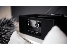 Charger l&#39;image dans la galerie, Radio PEAQ noire, écran affichant PEAQ, boutons et un bouton de volume, sur une surface.
