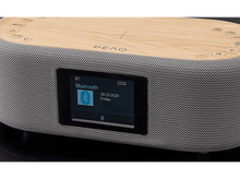 Charger l&#39;image dans la galerie, Un haut-parleur PEAQ avec un écran affichant la connexion Bluetooth et la date, sur fond sombre.
