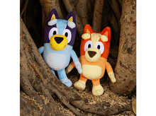 Charger l&#39;image dans la galerie, Deux peluches Bluey et Bingo se tiennent près d&#39;un tronc d&#39;arbre, dans un cadre naturel.
