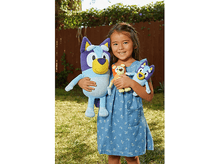 Charger l&#39;image dans la galerie, Une jeune fille tient trois peluches Bluey. Elle sourit dehors dans un endroit ensoleillé avec de l&#39;herbe et une clôture.
