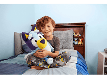 Charger l&#39;image dans la galerie, Un jeune garçon dans une pièce, tenant un grand jouet en peluche bleu en forme de chien, souriant.
