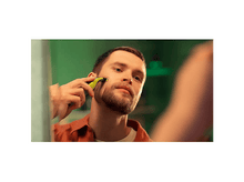 Charger l&#39;image dans la galerie, Un homme se rase la barbe devant un miroir. Il tient une tondeuse jaune et noire. Mur vert en arrière-plan.

