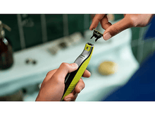 Charger l&#39;image dans la galerie, Une personne tenant un rasoir Philips OneBlade, avec une lame détachée, dans une salle de bain.
