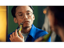 Charger l&#39;image dans la galerie, Homme se rasant la moustache dans un miroir, utilisant une tondeuse verte et noire.
