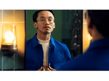 Charger l&#39;image dans la galerie, Un homme en veste bleue se regarde dans un miroir, avec une salle de bain en arrière-plan.
