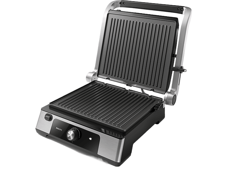 Un grill électrique ouvert avec une surface de cuisson noire et nervurée et un cadre argenté. Le grill est sur une surface noire.
