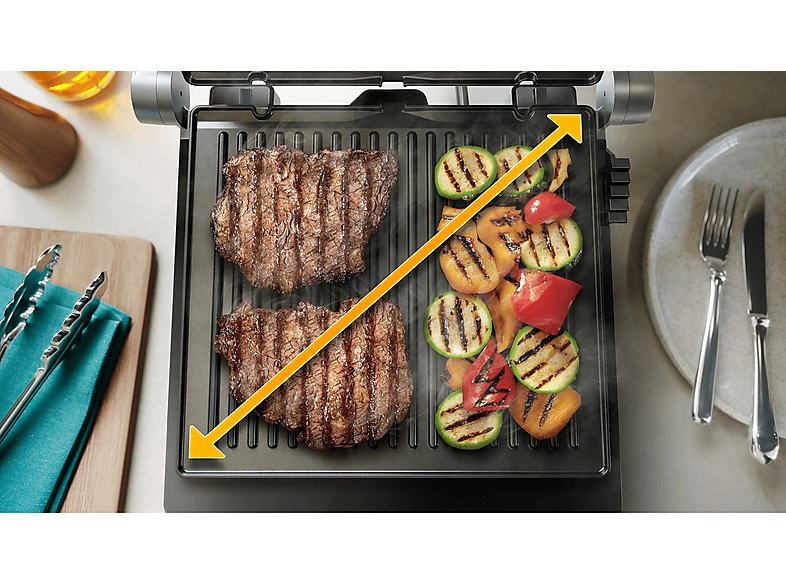 Gril avec deux steaks et légumes grillés, avec des flèches jaunes indiquant la zone de cuisson.