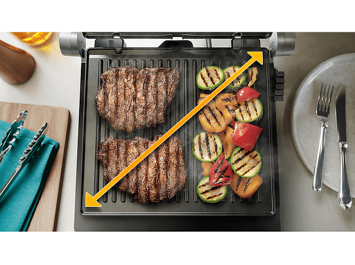 Gril avec deux steaks et légumes grillés, avec des flèches jaunes indiquant la zone de cuisson.