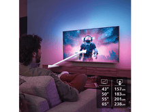 Charger l'image dans la galerie, Une personne regardant une télévision avec une image d'astronaute, entourée de lumières violettes et bleues.
