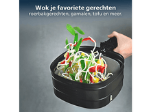 Charger l&#39;image dans la galerie, Un wok noir avec des nouilles, des poivrons rouges et jaunes et des haricots verts. Une main tient le wok. Texte en haut : Wok vos plats préférés.
