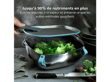 Charger l&#39;image dans la galerie, Une personne soulève le couvercle d&#39;une casserole fumante de brocolis. La casserole est en acier inoxydable avec des accents bleus. Couteau et planche à découper en bois présents.
