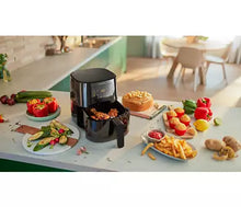 Charger l&#39;image dans la galerie, Friteuse à air noire avec aliments cuits et autres plats sur un plan de travail blanc.
