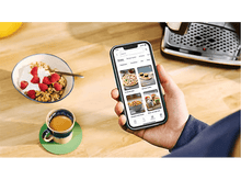 Charger l&#39;image dans la galerie, Personne tenant un téléphone avec une application, petit-déjeuner et café à proximité.
