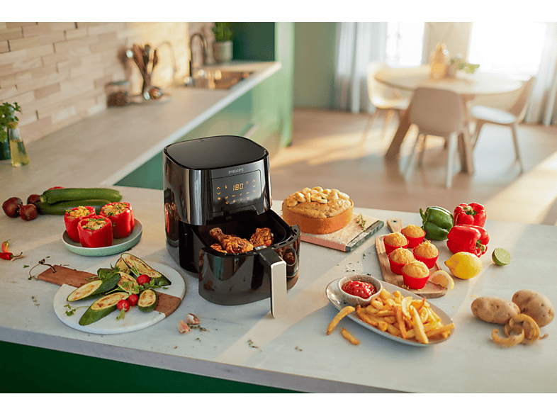 Un airfryer avec du poulet, divers aliments et ingrédients comme des poivrons, des courgettes et des pommes de terre.