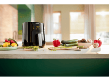 Charger l&#39;image dans la galerie, Friteuse à air Philips noire, avec légumes et aliments sur un comptoir.
