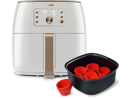 Une friteuse à air Philips blanche et dorée avec un panier noir et des moules à muffins en silicone rouge.