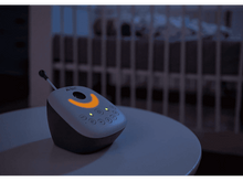 Charger l&#39;image dans la galerie, Babyphone sur une table. Lit bébé en arrière-plan. Lueur jaune.
