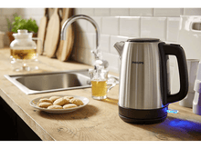 Charger l&#39;image dans la galerie, Bouilloire en acier inoxydable avec poignée noire et lumière bleue, eau du robinet, biscuits sur une assiette.
