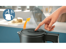 Charger l&#39;image dans la galerie, Personne appuyant sur un bouton d&#39;une bouilloire électrique noire.
