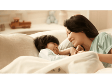 Charger l&#39;image dans la galerie, Une mère et un enfant se sourient en étant au lit sous une couverture blanche.
