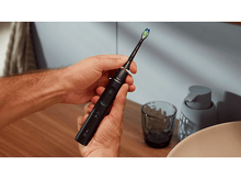 Charger l&#39;image dans la galerie, Personne tenant une brosse à dents Philips Sonicare noire. La brosse a un manche noir.
