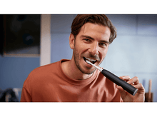 Charger l&#39;image dans la galerie, Un homme se brossant les dents avec une brosse à dents électrique noire et blanche.
