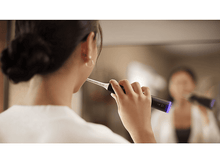 Charger l&#39;image dans la galerie, Une femme se brossant les dents devant un miroir avec une brosse à dents Philips Sonicare.
