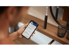 Charger l&#39;image dans la galerie, Homme utilisant un téléphone avec une brosse à dents. Le téléphone affiche le temps et les données. Salle de bain.
