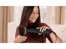 Charger l&#39;image dans la galerie, Une femme utilisant une brosse lissante, souriante, avec de longs cheveux bruns.
