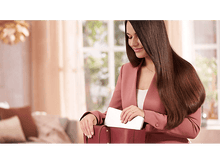 Charger l&#39;image dans la galerie, Une femme met une tablette dans un sac à main rouge. Elle porte un costume rose. Le fond est clair.
