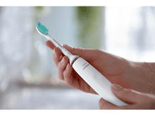 Charger l&#39;image dans la galerie, Mains d&#39;une personne tenant une brosse à dents électrique, avec la tête de brosse en haut. Manche blanc.
