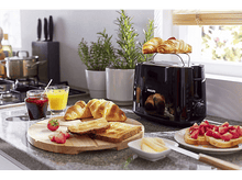 Charger l&#39;image dans la galerie, Scène de petit-déjeuner. Grille-pain avec croissants dessus. Toast, confiture, jus d&#39;orange et fraises sur une table.
