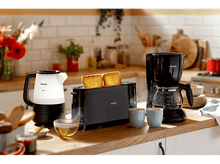 Charger l&#39;image dans la galerie, Appareils de cuisine. Grille-pain avec pain, cafetière et bouilloire sur un comptoir en bois.
