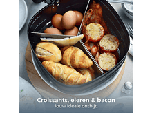 Charger l&#39;image dans la galerie, Plateau de petit-déjeuner avec croissants, œufs, bacon et tomates. Comprend des petits pains. Assiette blanche, planche en bois et couverts visibles.
