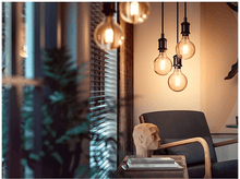 Charger l&#39;image dans la galerie, Plusieurs suspensions avec des ampoules Edison suspendues dans une pièce. Une sculpture en bois et une chaise visibles.
