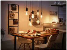 Charger l&#39;image dans la galerie, Une salle à manger avec une table en bois, des chaises, des ampoules suspendues et des éléments de cuisine.
