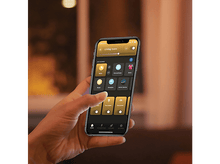 Charger l'image dans la galerie, Une main tenant un smartphone avec l'interface de l'application Hue affichée.
