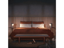 Charger l&#39;image dans la galerie, Une scène de chambre. Un lit avec une couverture orange brûlé, deux lampes sur les tables de chevet, un banc et un tapis.
