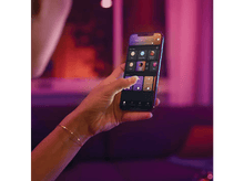 Charger l&#39;image dans la galerie, Une main tenant un smartphone affichant une interface d&#39;application de maison intelligente. Fond violet.
