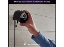 Charger l&#39;image dans la galerie, Une personne installe une caméra de sécurité noire sur un mur en bois. Le texte indique &#39;Hue Bridge requis&#39;.
