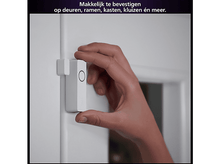 Charger l&#39;image dans la galerie, Une main tenant un capteur de porte intelligent blanc. Le capteur est fixé à un cadre de porte blanc.
