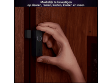 Charger l&#39;image dans la galerie, La main d&#39;une personne tenant un capteur de teinte noir à côté d&#39;une porte marron foncé.
