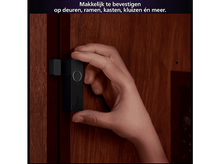 Charger l&#39;image dans la galerie, La main tient un appareil noir sur une porte en bois.
