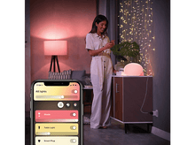Charger l&#39;image dans la galerie, Femme utilisant un téléphone, près d&#39;une lampe et d&#39;une armoire. Smartphone affiche une interface d&#39;application.
