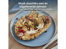 Charger l&#39;image dans la galerie, Brochettes grillées avec légumes et poulet sur pain pita, servies sur une assiette bleue. Table en bois et serviette en arrière-plan.
