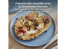 Charger l&#39;image dans la galerie, Chachlik grillé sur pain pita, avec légumes et sauce sur une assiette bleue. Table en bois avec texte en français.
